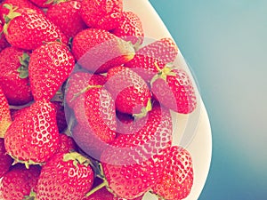 Strawberries on a plate, gray background. White dishes and delicious red large garden strawberries. Healthy food