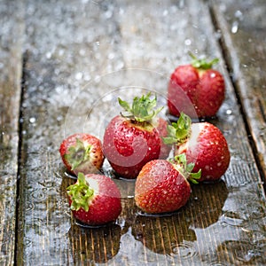 Strawberries in the rain on a wooden table close-up