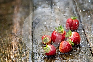 Strawberries in the rain on a wooden table close-up