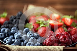 Strawberries, raspberries, blueberries, blackberries on a separate dish close-up on a solid concrete background. Healthy eating