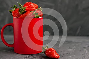 Strawberries in a red Cup on a grey concrete background