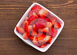 Strawberries on square bowl on wood from above