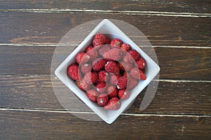 Strawberries in a square bowl on wood from above