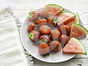 Strawberries and watermelon slices on a white plate