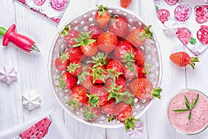 Strawberries in white ceramic bowl and pink strawberry milkshake or cocktail