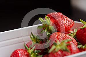 Strawberries in a white container. Background of red ripe berries