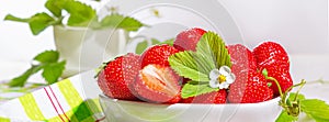 Strawberries in white porcelain bowl on a table. Bowl filled with juicy fresh ripe red strawberries