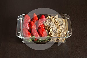 Strawberries and whole grains with dark chocolate on a black wooden table.