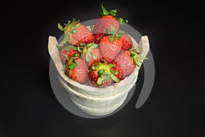 Strawberries in wooden basket on a black background