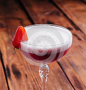 Strawberry alcoholic cocktail with foam on wood