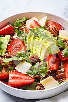 Strawberry and avocado salad with arugula, parmesan, nuts and lemon zest