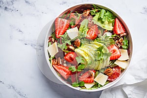 Strawberry and avocado salad with arugula, parmesan, nuts and lemon zest