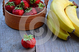 Strawberry in a basket and bananas on a wooden background. Ingredients for smoothies, yoghurt, cocktail. Yogurt with fresh strawbe