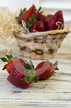 Strawberry in basket and on table on wooden background