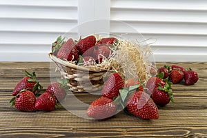 Strawberry in basket and on table on wooden background