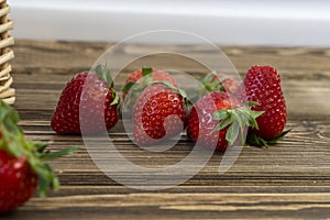 Strawberry in basket and on table on wooden background