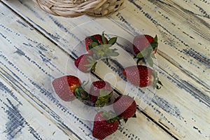 Strawberry in basket and on table on wooden background