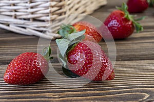 Strawberry in basket and on table on wooden background