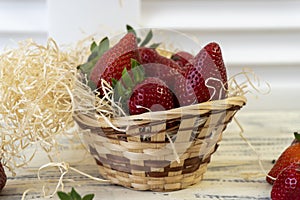 Strawberry in basket and on table on wooden background