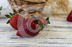 Strawberry in basket and on table on wooden background