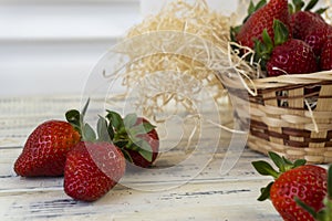 Strawberry in basket and on table on wooden background