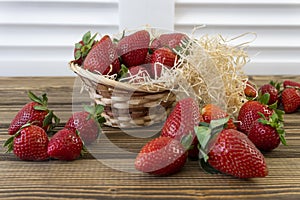 Strawberry in basket and on table on wooden background