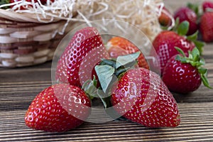 Strawberry in basket and on table on wooden background