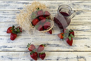 Strawberry in basket and on table on wooden background, strawberry juice in jug