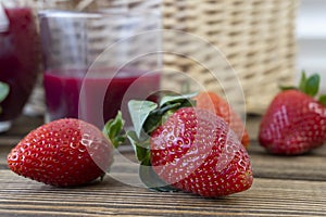 Strawberry in basket and on table on wooden background, strawberry juice in jug