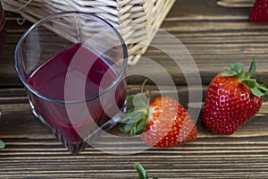 Strawberry in basket and on table on wooden background, strawberry juice in jug