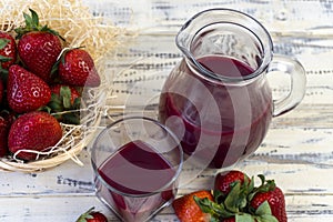 Strawberry in basket and on table on wooden background, strawberry juice in jug