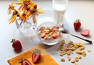 Strawberry berries on the morning table-corn flakes with strawberries in a glass dish with a bouquet and a yellow napkin, a glass