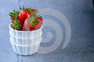 Strawberry berries in a white bowl on a concrete table. Place for text. Strawberries in a plate - dessert. Healthy food