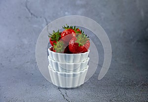 Strawberry berries in a white bowl on a concrete table. Place for text. Strawberries in a plate - dessert. Healthy food. Breakfast