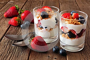 Strawberry and blueberry parfaits against a dark wood background