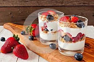 Strawberry and blueberry parfaits on a serving board against a dark background