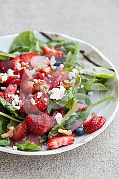 Strawberry blueberry walnut spinach salad close up shot vertical