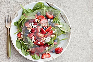 Strawberry blueberry walnut spinach salad full top view with fork