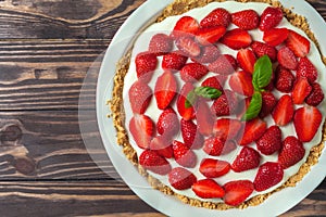 Strawberry cheesecake with basil leaves, in a red ceramic baking dish