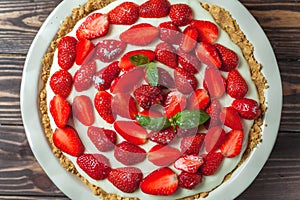 Strawberry cheesecake with basil leaves, in a red ceramic baking dish