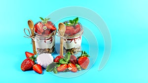 Strawberry cheesecake in glass jar with fresh strawberries and cream cheese Isolated on a blue background. Copy space. Healthy