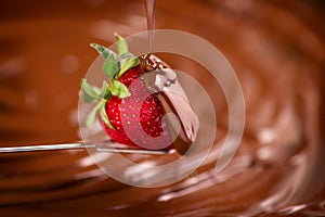 Strawberry in chocolate over swirl brown background. Melted Chocolate pouring on fresh ripe juicy strawberry close up. Dessert