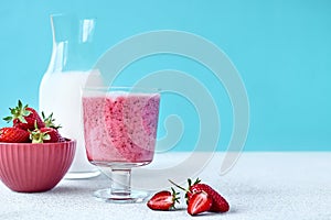Strawberry coconut milkshake, frappÃ© or smoothie in drinking glass on light blue background. Healthy vegan diet refreshing drink