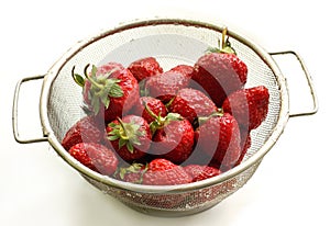 A strawberry is in a colander