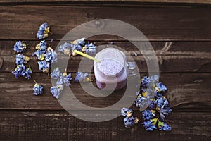 Strawberry and cranberry smoothie with dried flowers on a wooden table