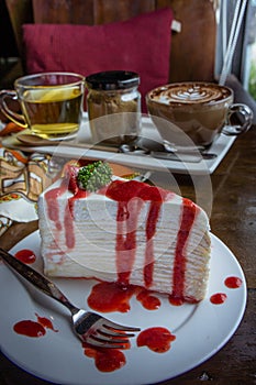 Strawberry crape cake on wood table in coffee shop , dessert tas