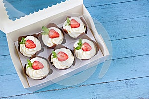 Strawberry cupcakes in delivery box, sweet gift, food delivery, blue wooden board