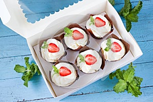 Strawberry cupcakes in delivery box, sweet gift, food delivery, mint leaves, blue wooden board