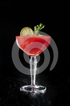 Strawberry daiquiri cocktail with lime, strawberry syrop, cherry and mint on black background.