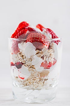 Strawberry dessert in a plate with ice cream and cream on a white wooden background